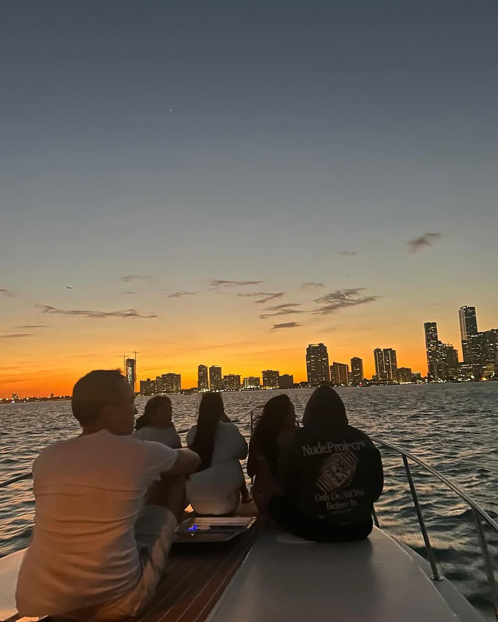 Guests sitting in silhouette watching the sun set behind the Miami skyline
