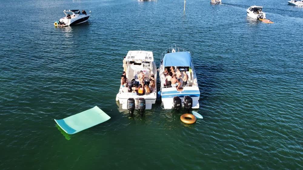 Two LuxSea boats rafted together at anchor, a float mat and ring in the water alongside