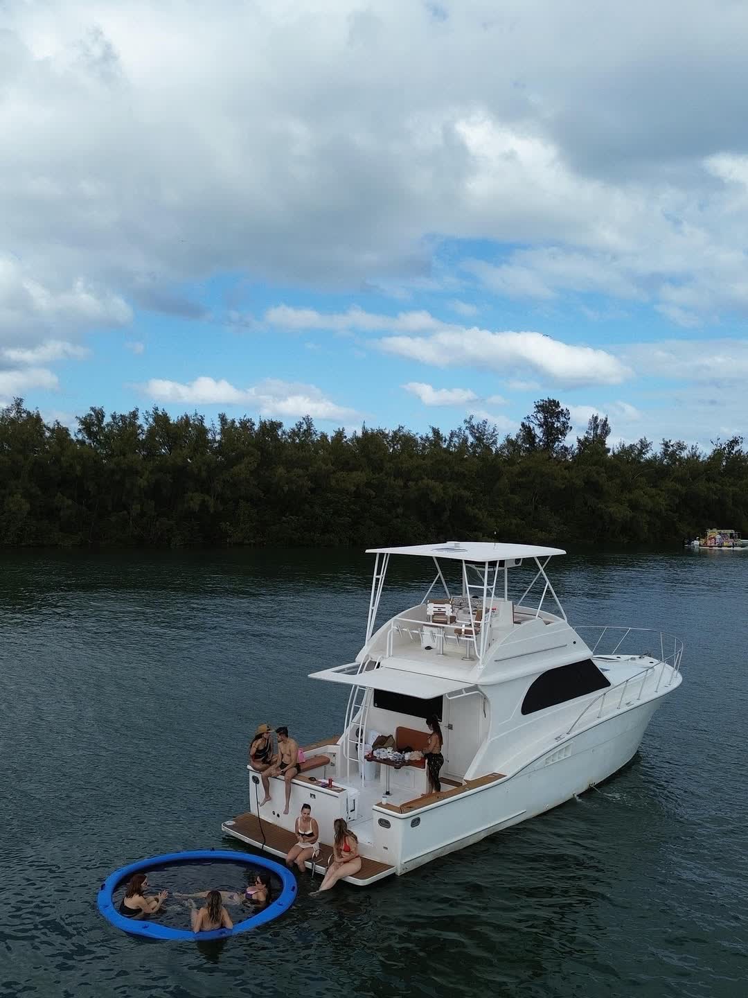 The Chris Craft 45 anchored side-on in green water off a mangrove island, guests on deck and a swim ring in the water