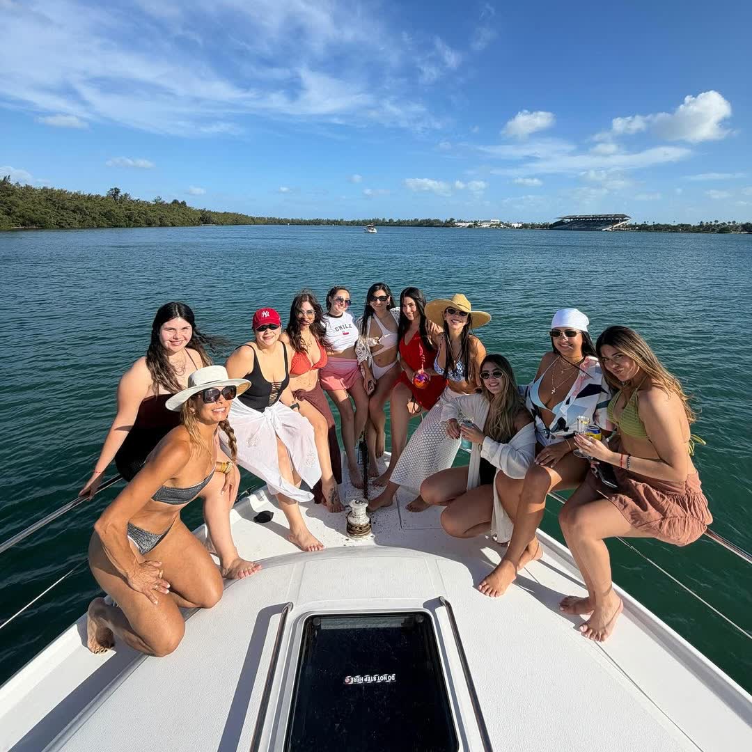 A large group of friends spread across the bow at the sandbar on a bright day