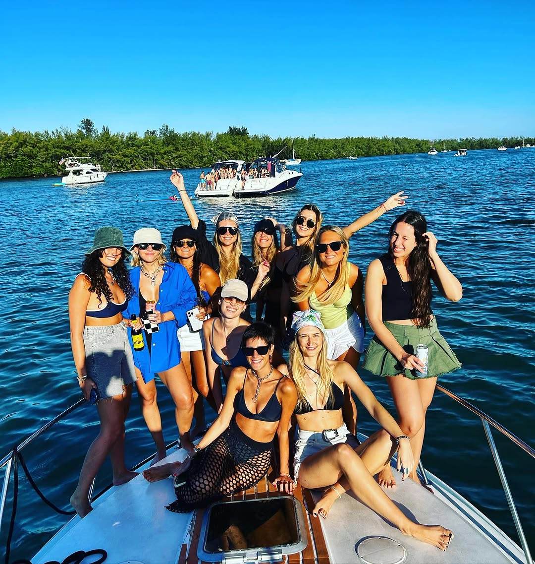 A bachelorette group filling the teak bow, mangroves and other boats behind them