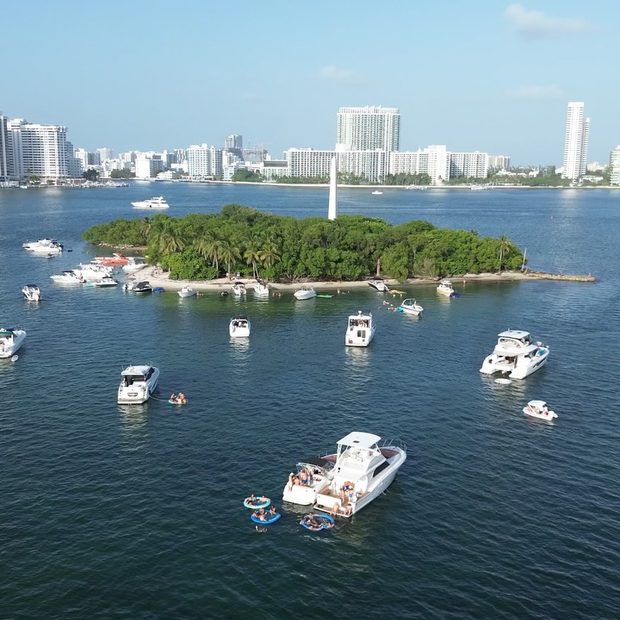 Vista aérea de botes fondeados alrededor de una isla de manglares frente a Miami Beach, con las torres de la ciudad detrás