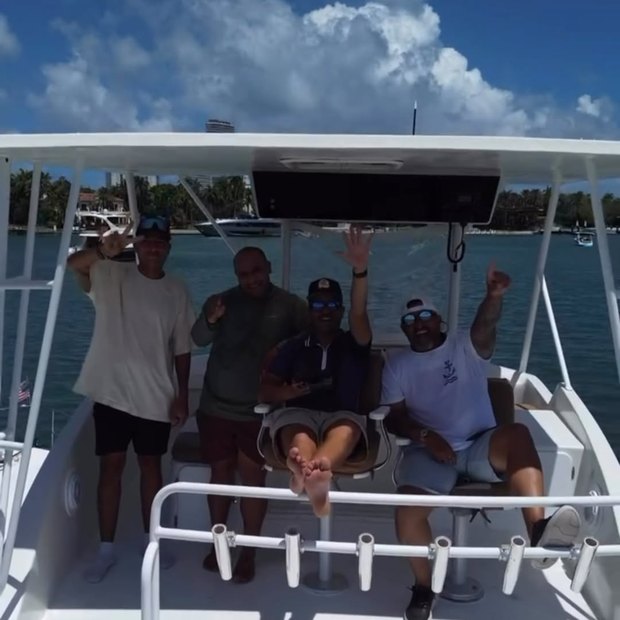 Invitados de pie en la bañera cubierta con los brazos en alto, saludando a la cámara