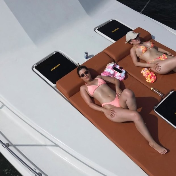 Dos invitadas tomando sol en los cojines de proa a media tarde