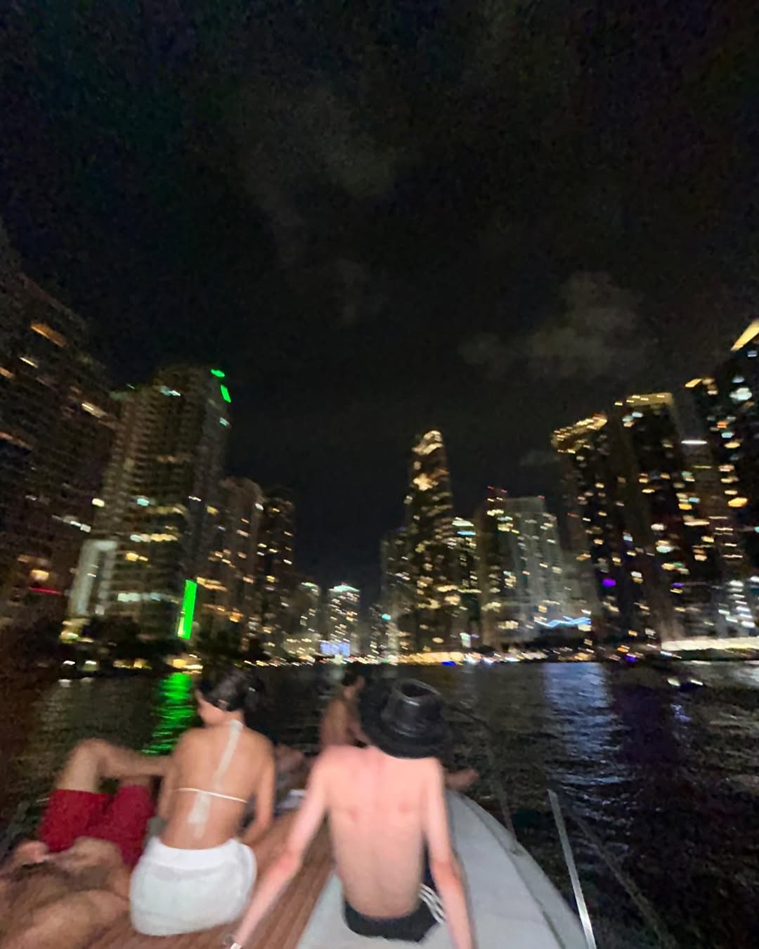 The city lights across the water at night, seen from the boat