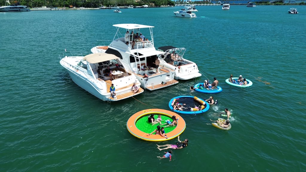 The three LuxSea boats rafted together on the bay with four floating pools tied off the sterns and swimmers in the water between them