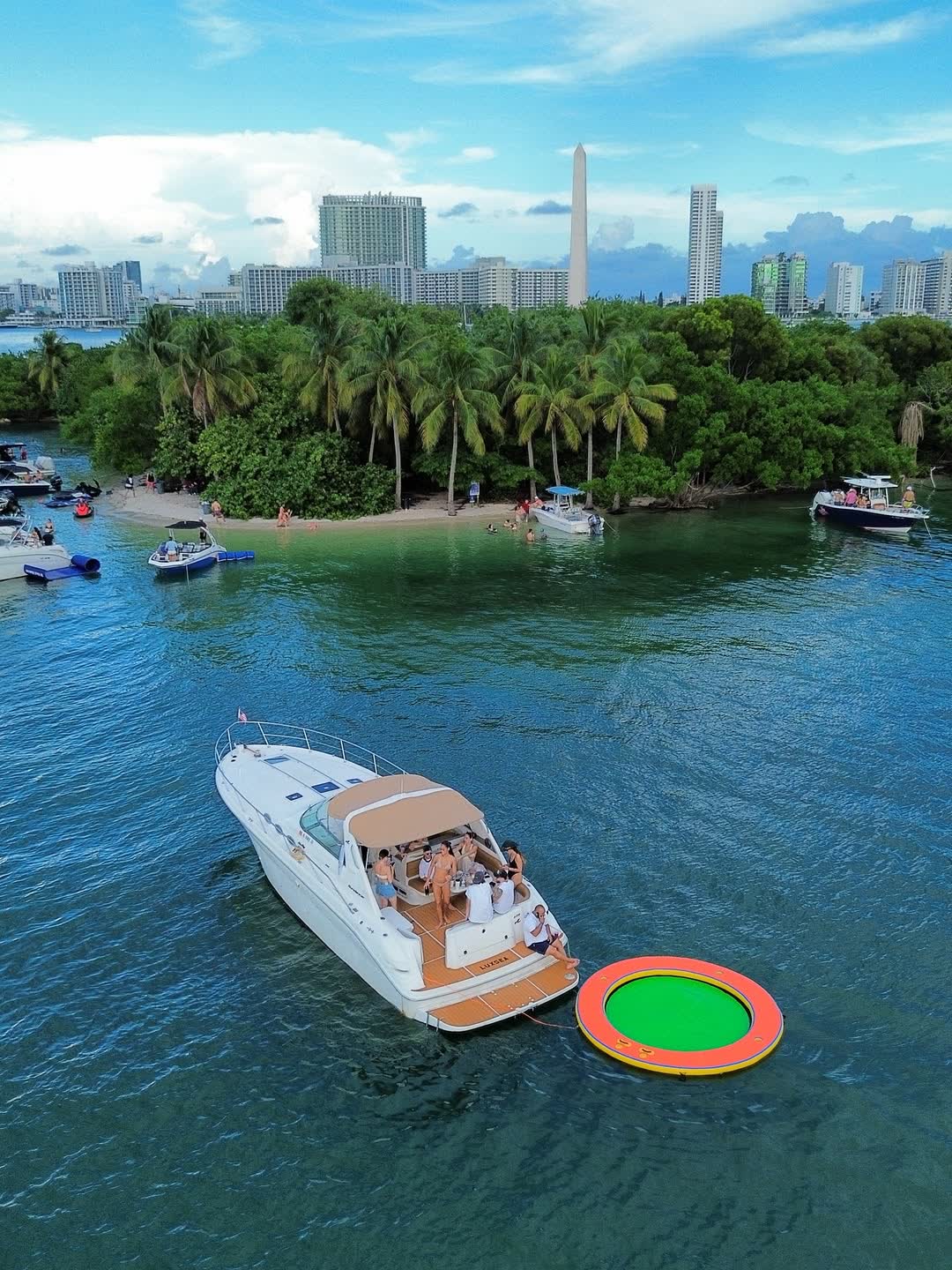 The Sea Ray Sundancer anchored off a mangrove island with a float in the water and the Miami skyline behind it