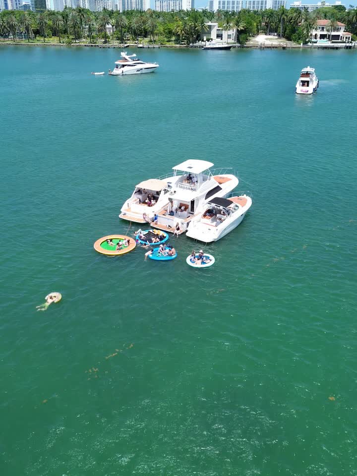 Two LuxSea boats rafted together at the sandbar with floats out and swimmers in the shallows